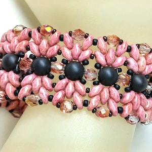 May include: A pink and black beaded bracelet with a floral design. The bracelet is made with small, round beads and features a repeating pattern of flowers.