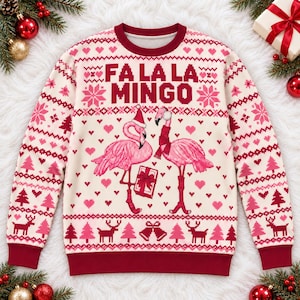 May include: A cream-colored crewneck sweater featuring a red and pink holiday-themed knit pattern. The center displays two pink flamingos, one wearing a Santa hat and the other a scarf, with the text FA LA LA MINGO printed above.