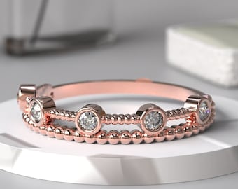 May include: A rose gold ring with a beaded band and five round clear stones.