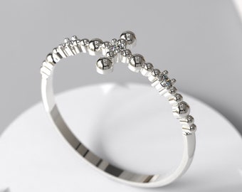 May include: A silver ring featuring a cross design made of small beads and set with tiny diamonds.