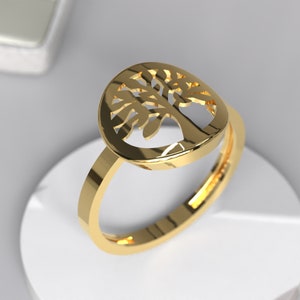 Può includere: Un anello d'oro con un design ad albero della vita. L'anello è realizzato in metallo lucido e ha una finitura liscia.