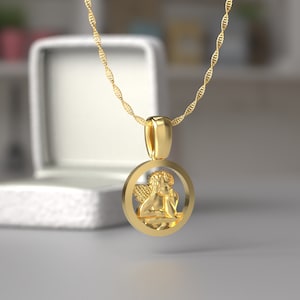 Peut inclure: Un collier en cha&icirc;ne dor&eacute;e avec un pendentif rond repr&eacute;sentant une figurine de ch&eacute;rubin d&eacute;taill&eacute;e.