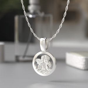 Peut inclure: Collier en argent avec un pendentif rond repr&eacute;sentant un ange d&eacute;taill&eacute;.