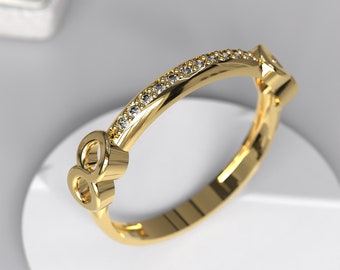 May include: A gold ring with a diamond-encrusted band and a unique infinity symbol design.