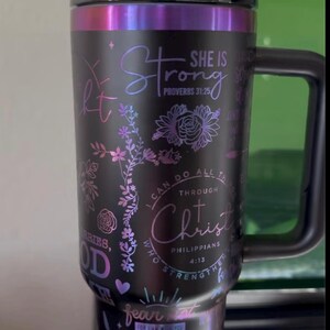 May include: Black stainless steel tumbler with a floral design and inspirational quotes. The quotes include "She is Strong, Proverbs 31:25", "I can do all things through Christ, Philippians 4:13", and "Fear not, for I am with you, Isaiah 41:10".