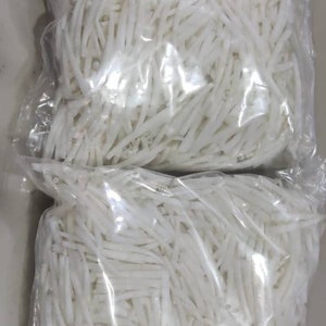 May include: Two clear plastic bags filled with white, julienned vegetables, possibly daikon radish or similar. The vegetables are tightly packed and appear fresh. The bags are sealed and ready for sale.