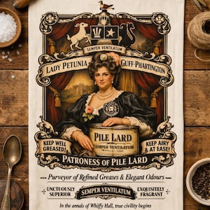 May include: A vintage-style kitchen towel featuring a portrait of a woman and the words "Pile Lard." The design includes ornate borders, text, and illustrations, with the phrases "Keep Well Greased" and "Keep Airy & At Ease!"