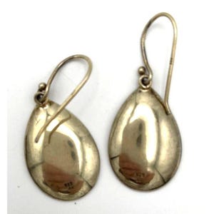 May include: A pair of teardrop-shaped earrings with a polished, metallic finish. The earrings have a hook closure and a small, round accent near the top. The surface of the earrings reflects light, creating a shiny appearance. The earrings are likely made of a silver alloy.