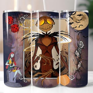 May include: A set of three stainless steel tumblers with a Halloween theme. The tumblers feature a black and white illustration of Jack Skellington from The Nightmare Before Christmas. The tumblers are decorated with a variety of Halloween imagery, including bats, pumpkins, and a full moon.