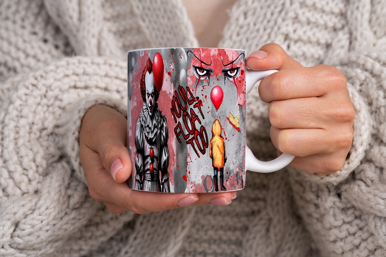 May include: White ceramic mug with a colorful graphic of a clown with red hair and a red balloon, a child in a yellow raincoat, and the text "YOU'LL FLOAT TOO".