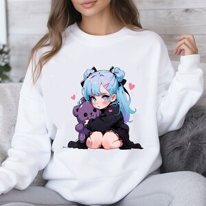 Puede incluir: Sudadera blanca con un estampado gr&aacute;fico de una chica de anime de pelo azul que sostiene un oso de peluche morado. La chica tiene lazos negros en el pelo y corazones rosas alrededor.