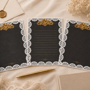 Könnte beinhalten: Drei schwarze Schreibkarten mit weißen Spitzeneinfassungen und goldenen Akzenten. Die Karten haben oben und unten ein dekoratives Golddesign. Eine Karte ist liniert, eine ist leer und eine hat ein gepunktetes Muster. Ein goldener Stift und ein Umschlag sind ebenfalls vorhanden.