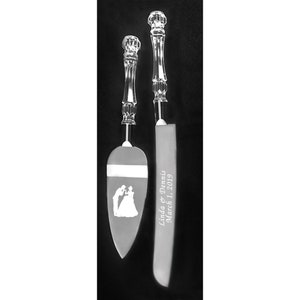 May include: A set of two silver wedding cake knives with crystal handles. The knife on the left has a silhouette of a bride and groom. The knife on the right has the text "Linda & Dennis March 1, 2019" engraved on the blade.