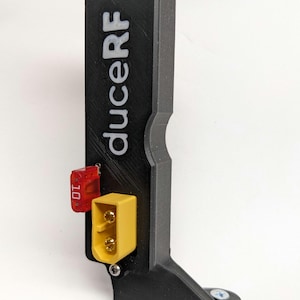May include: A black 3D printed battery case with a yellow and gold connector and a red switch labelled "DT1". The case has the text "duceRF" printed on the side.