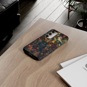 Op de afbeelding: Een zwarte telefoonhoes met een kleurrijk abstract ontwerp. De hoes heeft een uitsparing voor de camera en een textuur.