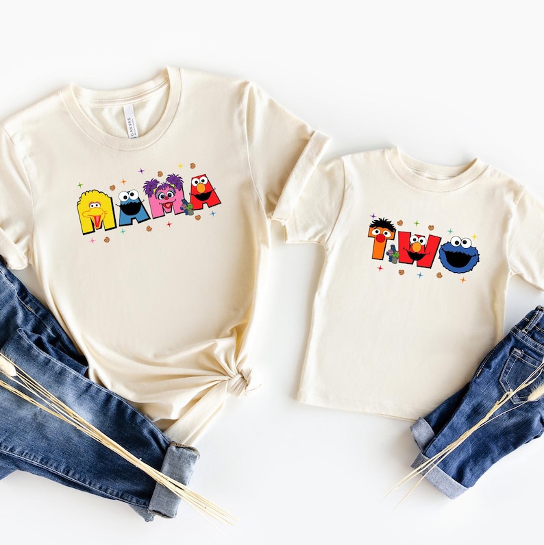 two white t-shirts with colorful cartoon character designs, including Smurfs and Cookie Monster, printed on them.
