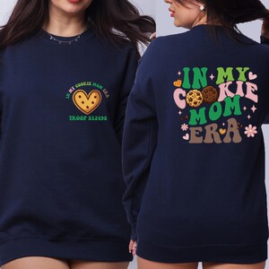 A woman wearing a navy blue sweatshirt with a graphic design on the back.
