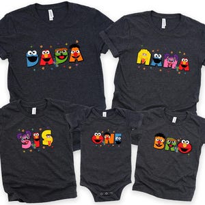 a collection of five gray t-shirts with colorful characters and text printed on them.