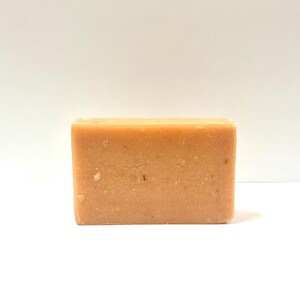May include: A rectangular bar of light orange soap with a grainy texture.
