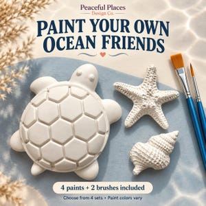 May include: A paint-your-own craft kit featuring white ceramic figures of a turtle, a starfish, and a seashell. The set includes two blue-handled paintbrushes. Text reads: Peaceful Places Design Co. PAINT YOUR OWN OCEAN FRIENDS 4 paints + 2 brushes included.