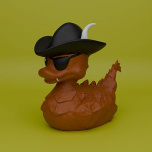Könnte beinhalten: Eine braune, drachenartige Gummiente mit einem schwarzen Piratenhut, einer schwarzen Augenklappe und einer Sonnenbrille. Die Ente hat ein weißes Horn und einen einzelnen Fangzahn. Der Hintergrund ist einfarbig gelb-grün.