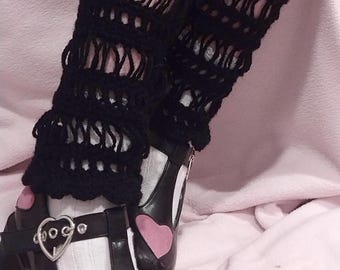 May include: Black crochet leg warmers with a delicate openwork pattern. The leg warmers are worn with black shoes with pink heart accents.