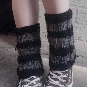 May include: A pair of black and gray striped leg warmers worn with black canvas high-top sneakers with floral embroidery.