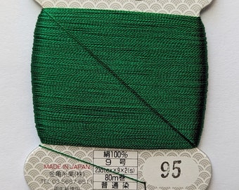 May include: A spool of green silk thread with a label that reads "絹手縫糸" (silk hand sewing thread) and "金亀" (Kin-Kame) in gold lettering. The label also includes the text "絹100%" (100% silk), "9号" (9 gauge), "23otex×9×2(s)", "80m巻" (80m spool), "普通染" (ordinary dye), and "95".