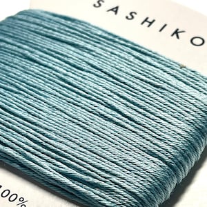 May include: A spool of light blue sashiko thread, 100% cotton, with a label that reads "Sashiko" and "30m".