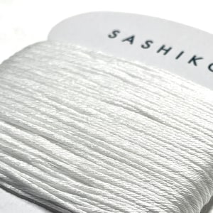 May include: White sashiko thread wound on a card with the text "SASHIKO" and "100%" and "30m".
