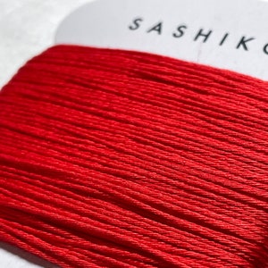 May include: A spool of red cotton thread labeled "Sashiko" and "Cotton 100%" with "30m" visible on the label.