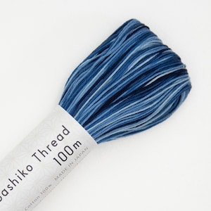 May include: A spool of blue and white ombre cotton thread labeled "Sashiko Thread 100m Made in Japan".