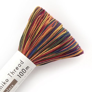 May include: A spool of colorful thread with a variety of colors including red, yellow, blue, and green. The label reads "niko Thread 100m Made in Japan". The thread is tightly wound and ready for use in sewing or embroidery projects.