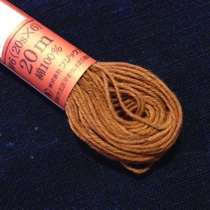 May include: A spool of brown embroidery floss with a label that reads "#6 (20s x 6) 20m 綿100% ◎ 株式会社 リジック 都市北区平野宮本町5番".