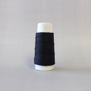 May include: A spool of black thread on a white bobbin with the word "cosmo" printed on the bobbin.
