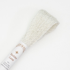 May include: A spool of white Sashiko Lamé thread with silver metallic accents. The label reads "Sashiko Lamé" and "40m Cotton 96% Polyester 4% MADE IN JAPAN".