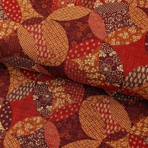 May include: Close-up of a fabric with a patchwork design. The fabric features overlapping oval shapes in shades of red, orange, and brown. Each oval has a unique pattern, including floral, geometric, and textured designs. The overall effect is a rich, warm, and detailed textile.