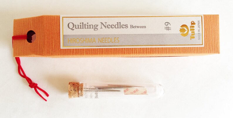 Puede incluir: Un paquete de agujas para acolchar Tulip en un tubo de vidrio. Las agujas son del tama&ntilde;o #9 y est&aacute;n hechas en Jap&oacute;n. El embalaje es naranja y blanco con el texto "Quilting Needles Between Hiroshima Needles".