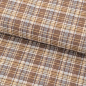 May include: A folded piece of fabric featuring a plaid pattern with intersecting lines in shades of brown, tan, cream, and pale blue. The textile displays a consistent woven texture throughout, with the pattern repeating across the surface.