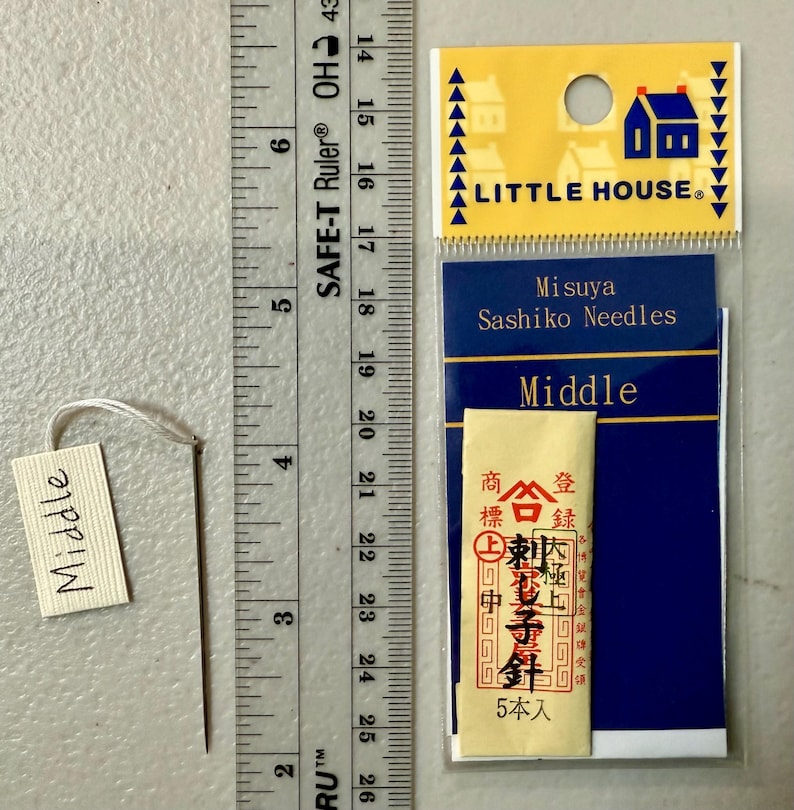 Pu&ograve; includere: Un pacchetto di aghi Sashiko Misuya etichettato "Medio". La confezione &egrave; blu e bianca con un piccolo logo di una casa e il testo "Little House". Gli aghi sono confezionati in una piccola busta bianca con testo giapponese.