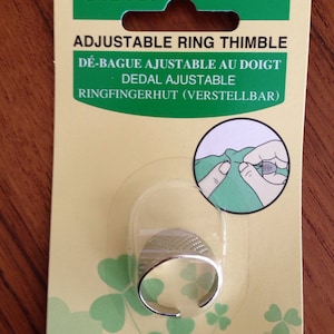 May include: A silver adjustable ring thimble with a clover leaf design on the packaging. The packaging is green and yellow with the text "Adjustable Ring Thimble" and "Clover Mfg. Co., Ltd. Japan".