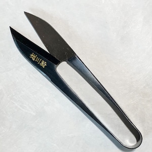 May include: Black fabric shears with a gold inscription that reads "製品質". The shears have a rounded handle and sharp blades.