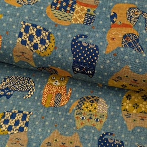 May include: Blue fabric with a repeating pattern of stylized cats. The cats feature patchwork designs in shades of blue, yellow, orange, and brown. The background is a light blue with small white polka dots, creating a whimsical and playful design.