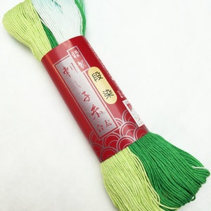 May include: A spool of green, light green, and white embroidery floss. The spool is labeled in Japanese with the text "2x Silk"