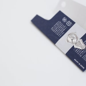 May include: A silver key-shaped bookmark with the words "MY SHELF" engraved on it. The bookmark is attached to a blue and white card with Japanese text and the words "MADE IN JAPAN".