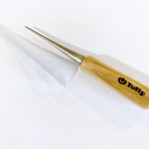 May include: A wooden handled needle tool with a metal tip and a clear plastic sheath. The handle is labeled "Tulip".