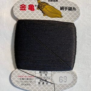 May include: A spool of black 100% silk thread for hand sewing. The label reads "Made in Japan" and "Kimono Sewing Thread" in Japanese. The spool is labeled with the number 69 and the thread size is 9. The thread is 80 meters long.
