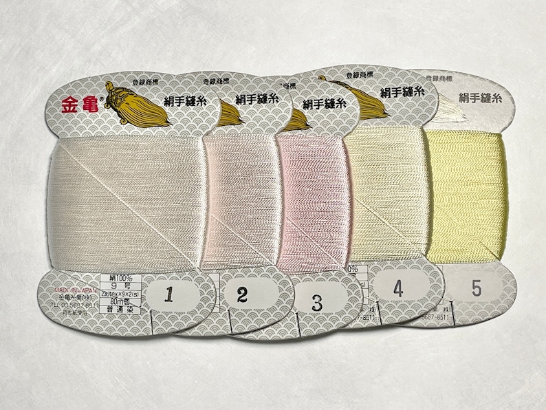 May include: Five spools of silk thread in varying pastel colors, labeled 1 through 5. The spools are on a white background. Each spool has a label with Japanese text and a gold turtle logo.