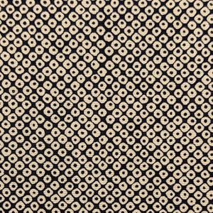 May include: Close-up of a fabric with a repeating pattern of small, cream-colored squares with a dark navy blue background. Each square has a small, dark circle in the center, creating a textured effect.