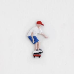 May include: Embroidered iron-on patch of a person skateboarding. The person is wearing a white shirt, blue shorts, and a red cap. The skateboard is red and black.